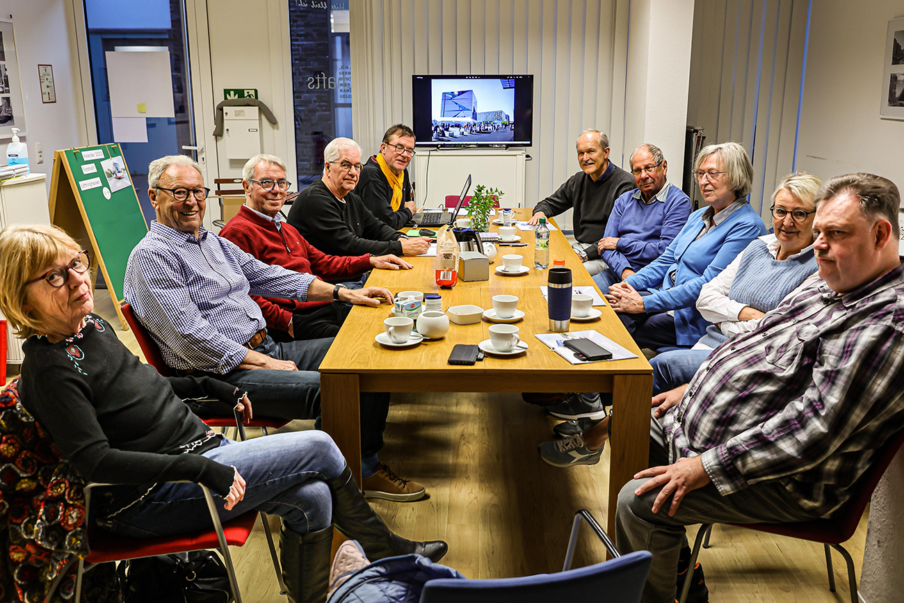 Fotogruppe sitzt zusammen am Tisch in der Nachbarschaftsagentur.