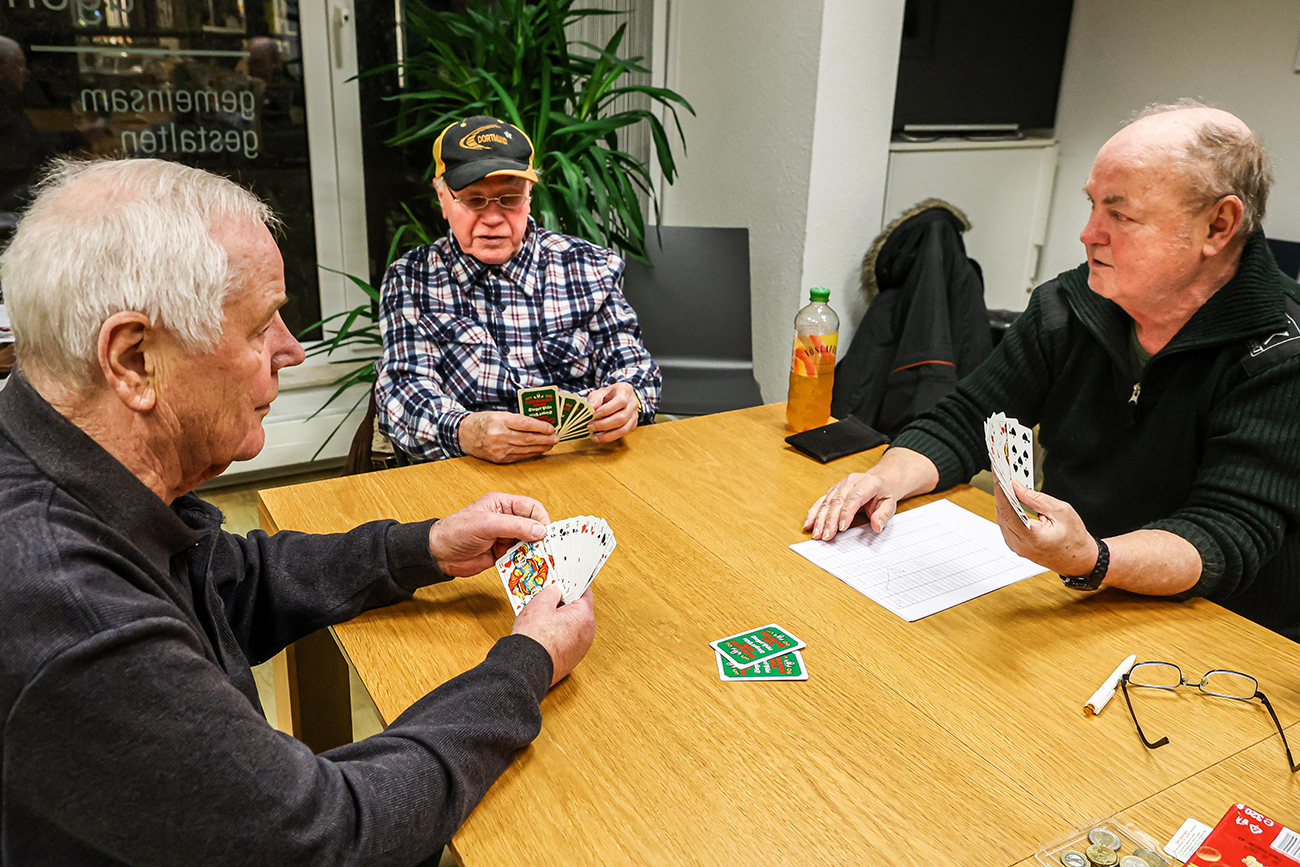 Männer sitzen am Tisch und spielen Skat.