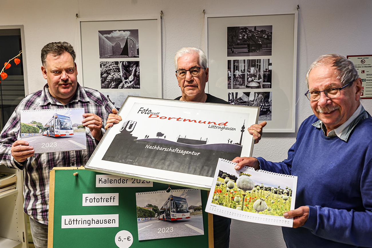 Männer zeigen Bilder des jährlichen Fotokalenders.