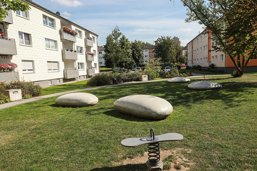 Außenanlagengestaltung mit Steinen neben einem Spielplatz.