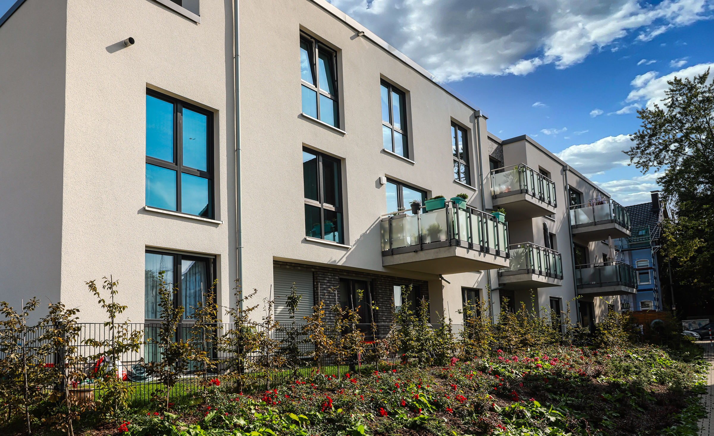 Modernes, gepflegtes Mehrfamilienhaus vor strahlend blauem Himmel.