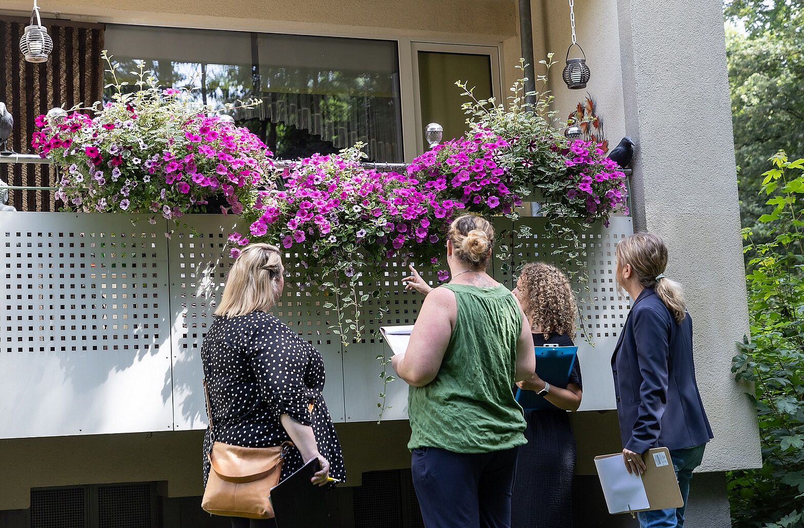 Vier Frauen stehen vor einem oppulent mit Petunien bepflanzten Balkon