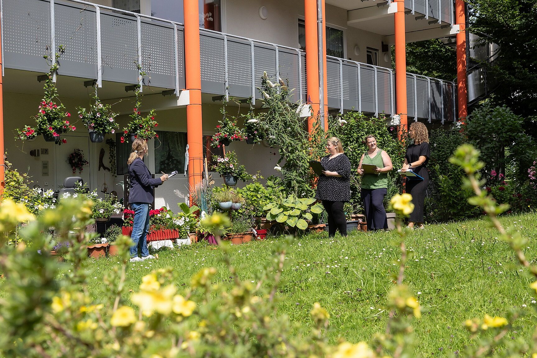 Die aus vier Frauen bestehende Blumen-Jury steht auf einer großen Wiesenfläche vor einer toll bepflanzen Terrasse