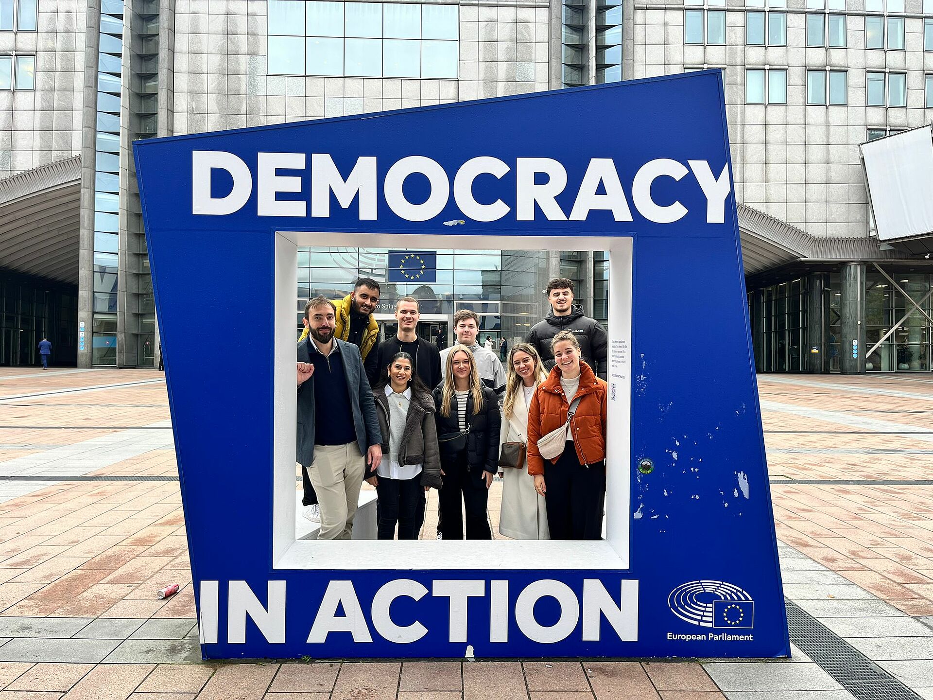 Gruppenbild junger Menschen mit einem Demokratie-Rahmen in Brüssel.